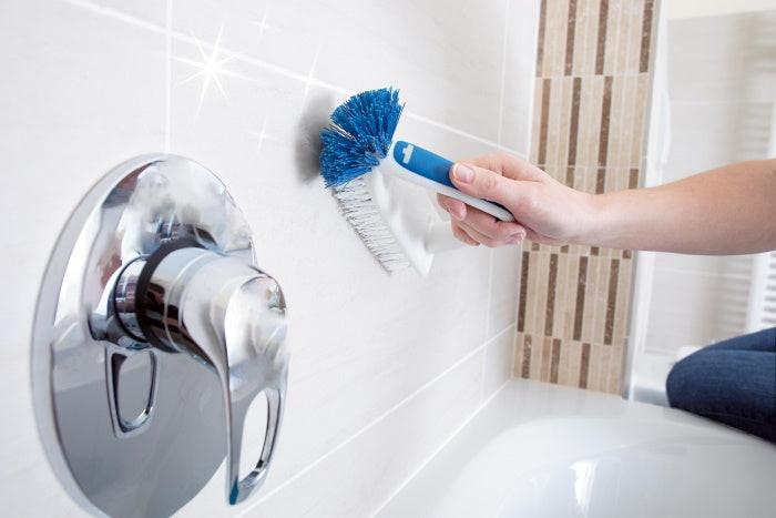 Unger robuste Flachbürste im Einsatz bei der Fugenreinigung neben einer glänzenden Armatur