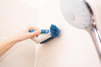Hand hält Unger Eckreinigungsbürste zum Reinigen der Fliesenfugen in der Dusche