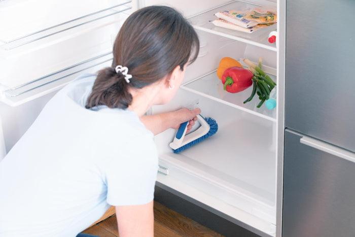 Frau reinigt Kühlschrankinnenraum mit der Unger Eckreinigungsbürste
