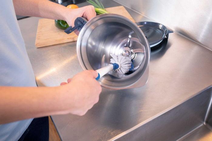 Person säubert eine Edelstahlrührschüssel mit der Unger Spülbürste Flex in einer modernen Küche