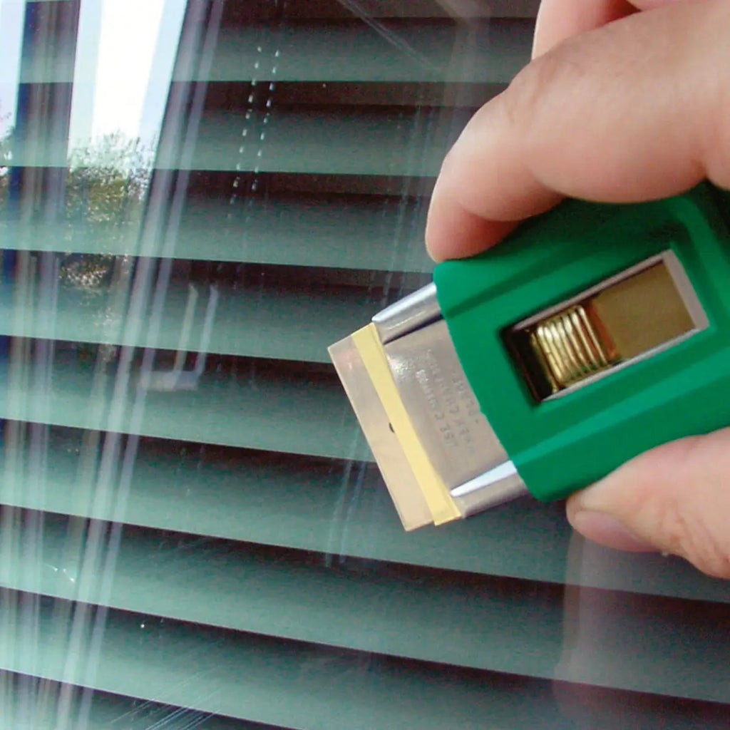 Hand mit grünem Unger Schaber aus dem ErgoTec Fensterputzer-Komplett-Set 6in1 AK015 bei der Glasreinigung