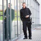 Gebäudereiniger mit UNGER ErgoTec Ninja 6in1 Fensterputzset AKN14 in Holster vor Glasfassade