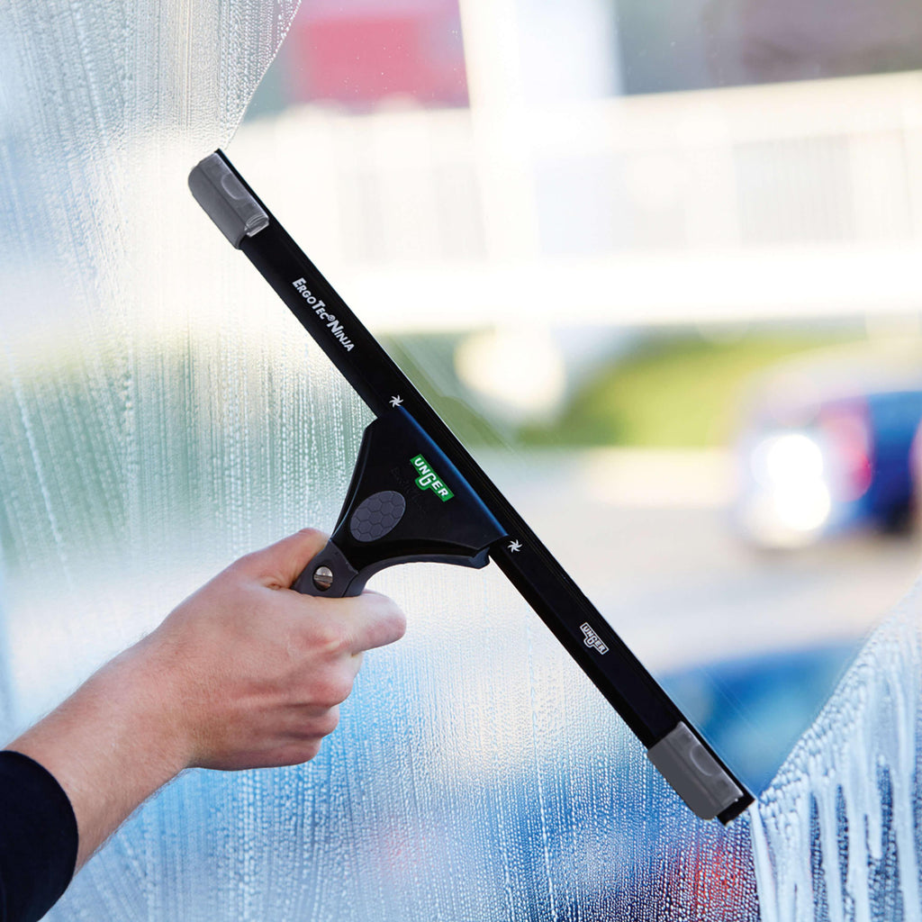 Hand mit Unger ErgoTec Ninja Fensterwischer beim Abziehen einer Glasfläche – Teil des 6in1 Fensterputzer-Sets AKN14
