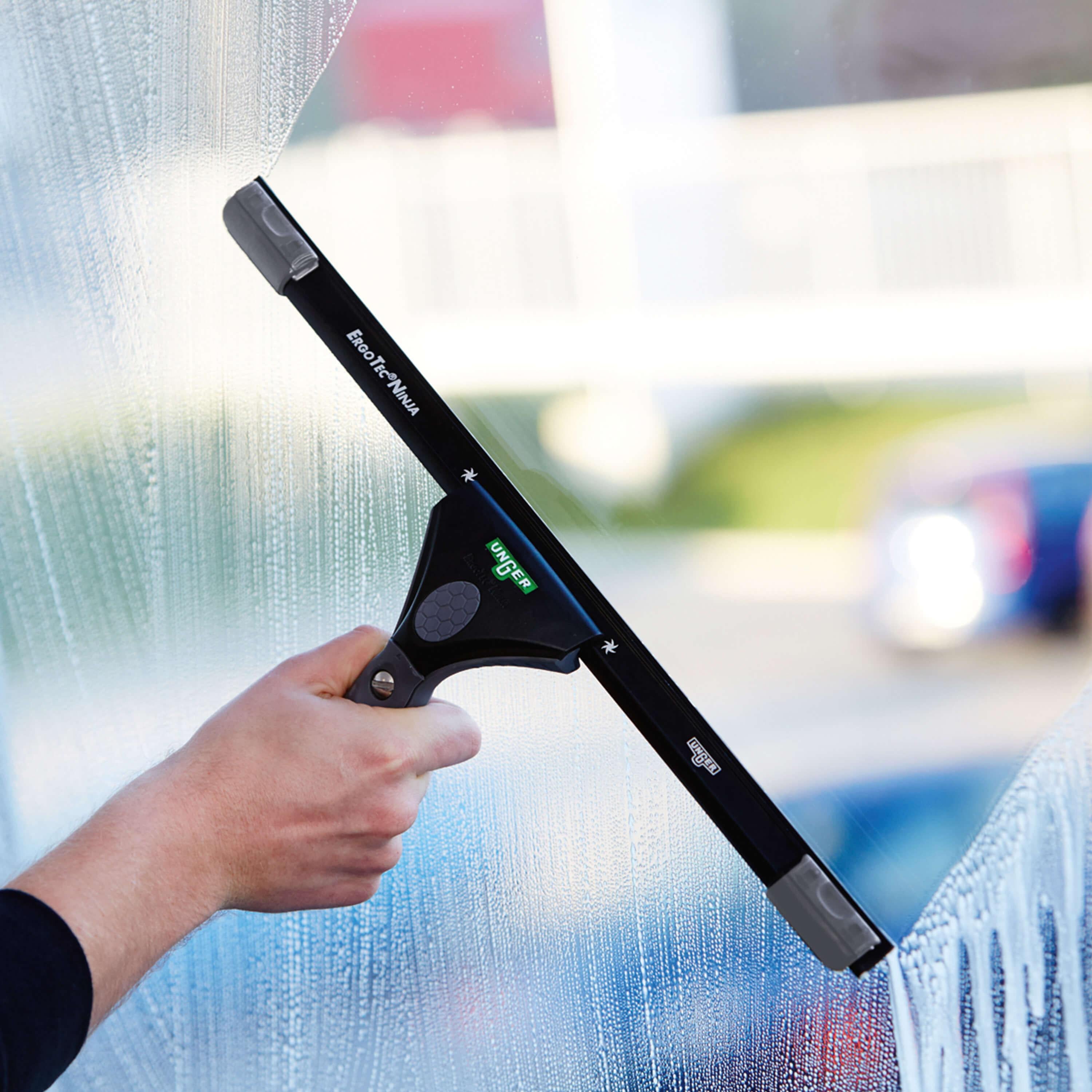 Hand mit Unger ErgoTec Ninja Fensterwischer beim Abziehen einer Glasfläche – Teil des 6in1 Fensterputzer-Sets AKN14