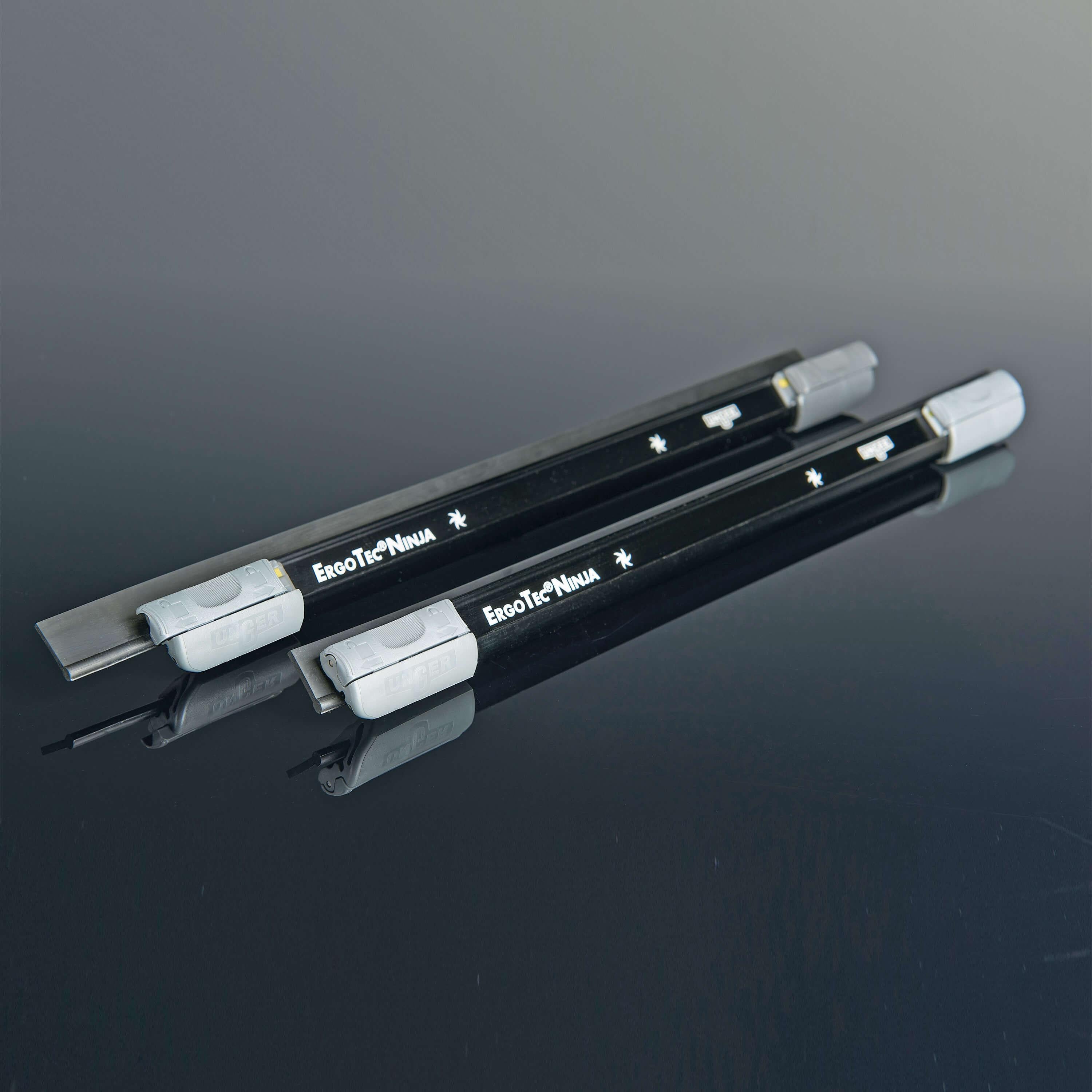Zwei schwarze Schienen des Unger ErgoTec Ninja Fensterwischers mit grauen Endkappen, liegend auf schwarzem Hintergrund – Zubehör des 6in1 Complete Kits AKN14