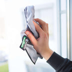 Hand wischt mit einem UNGER Mikrofasertuch der ErgoTec Ninja Serie über eine Fensterscheibe – Bestandteil des 6in1 Complete Kits AKN14