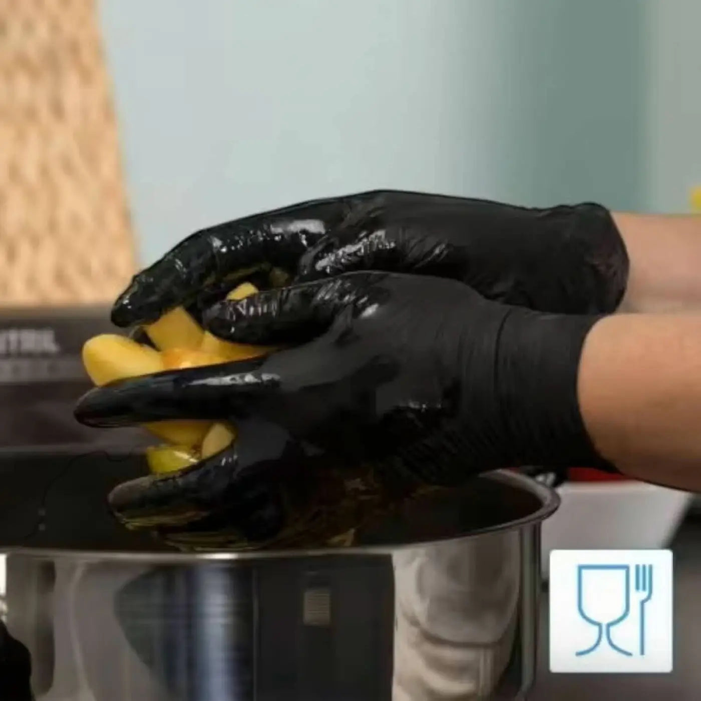 Black latexhandschuhe von arnomed puderfrei greifen gelbe kartoffelstücke über einem edelstahltopf