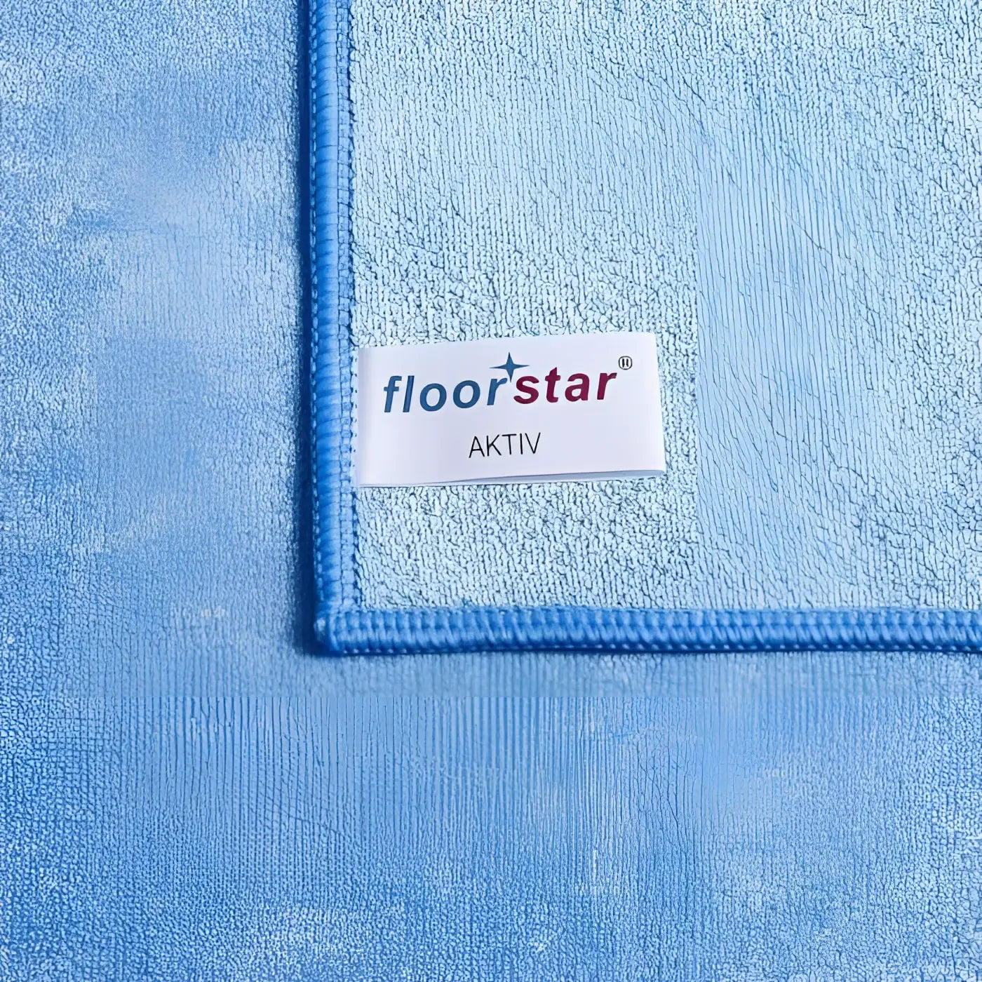 Lichtblaues plush mikrofasertuch floorstar aktiv mit gesticktem rand und weißem etikett premium strettuch