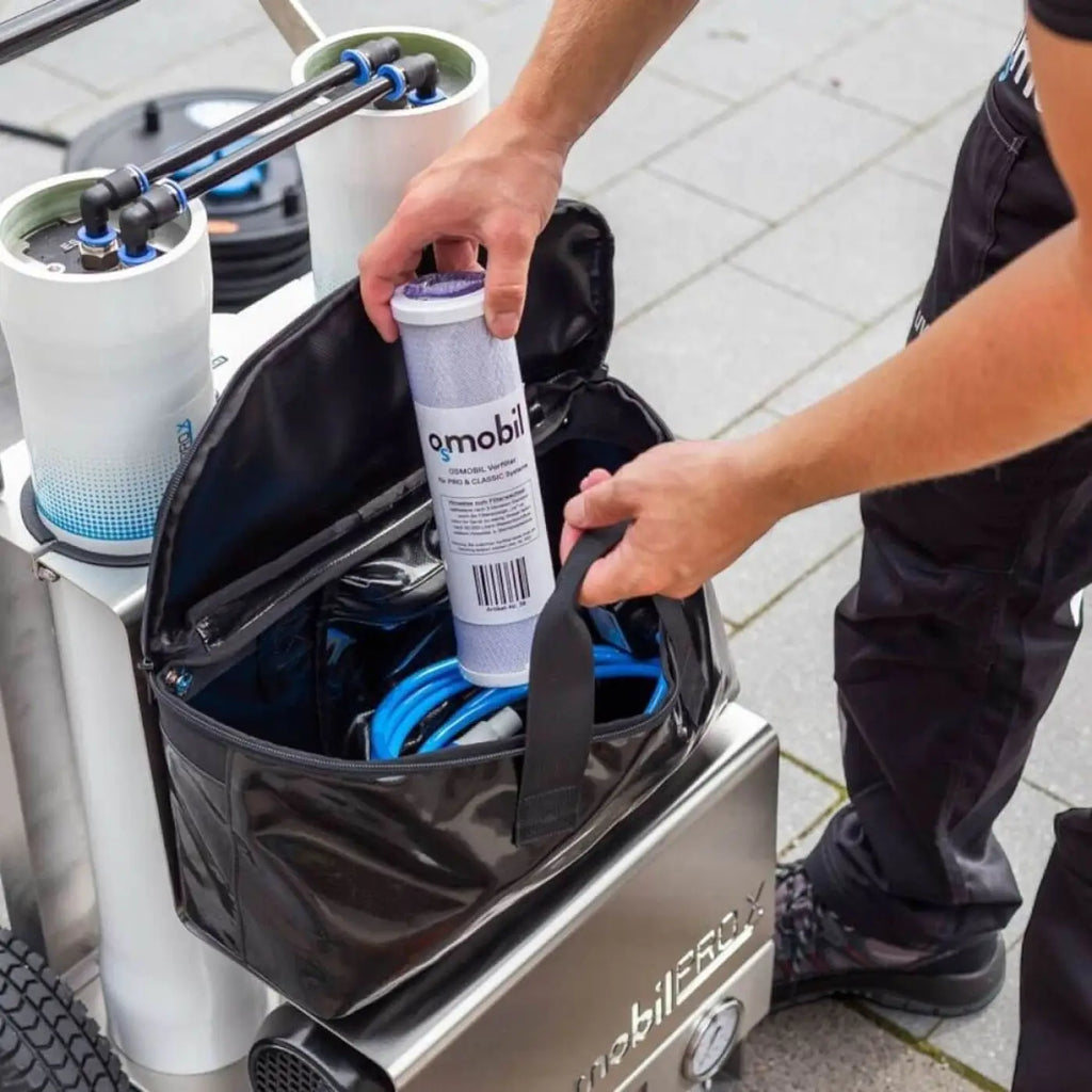 Ein weiß-grauer omobil wasserfilter kartusche mit schwarzem etikett wird für osmobil pro x glas pv und fassadenreinigung gehalten