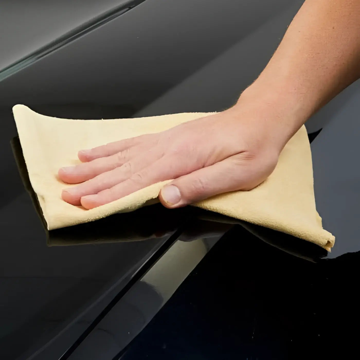 Beige mikrofasertuch zur autopflege verwendet zum polieren einer glänzenden schwarzen oberfläche mit sonax autoshampoo konzentrat 2l