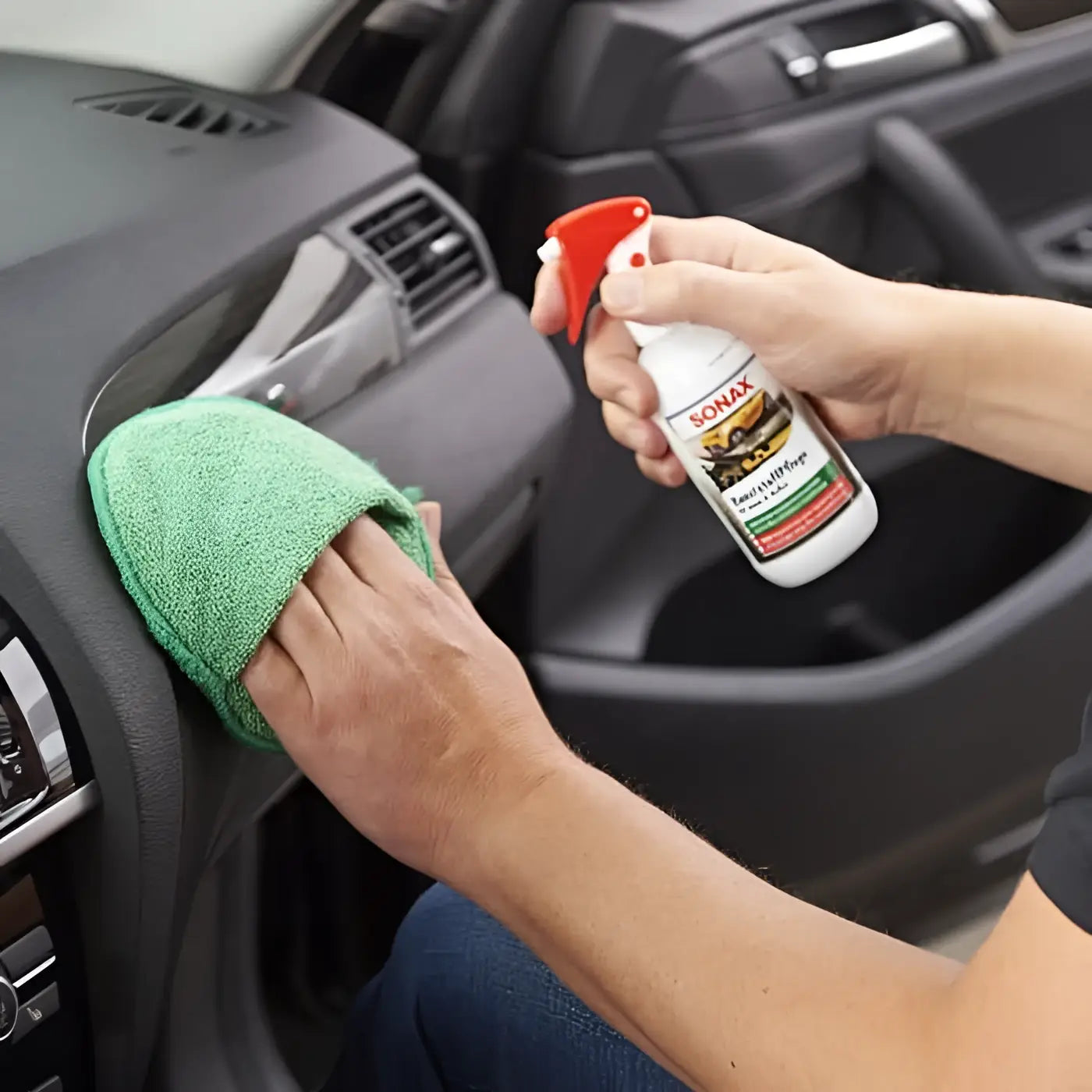 Eine weiße sohax sprayflasche mit roter düse wird zur reinigung des armaturenbretts im auto verwendet